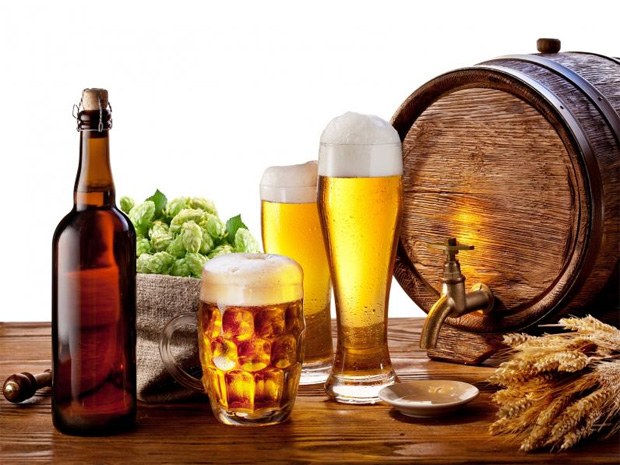 На фоне пивного бочонка стоит бутылка, два стакана и кружка с пивом