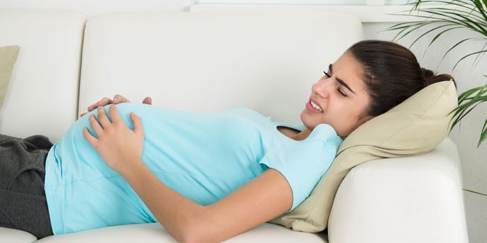 Беременная девушка лежит на диване