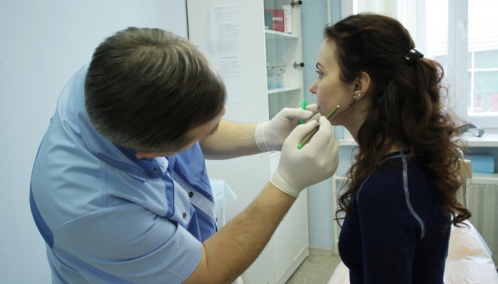 Косметолог осматривает кожу лица перед введением филлеров